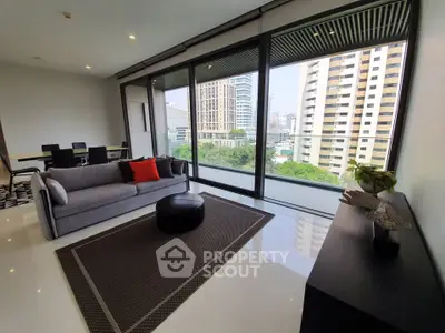Modern living room with large windows and city view, featuring sleek furniture and stylish decor.