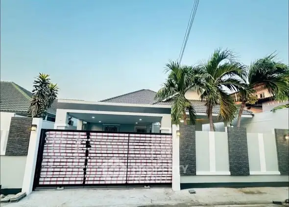 Modern house exterior with gated entrance and palm trees