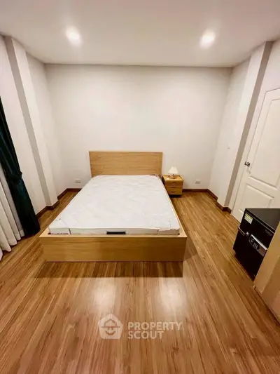 Spacious bedroom with wooden flooring and modern furniture.