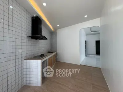 Modern kitchen with sleek design and open layout, featuring tiled walls and built-in gas stove.