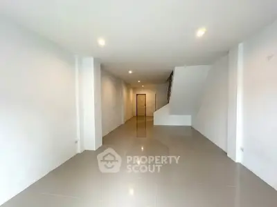 Spacious open-plan living area with sleek tile flooring and modern lighting.