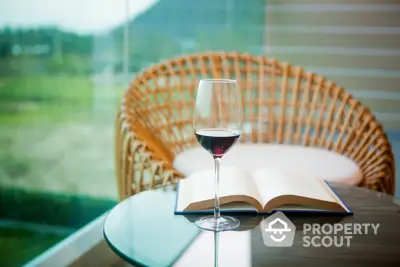 Stylish balcony with wicker chair and glass table, perfect for relaxation.