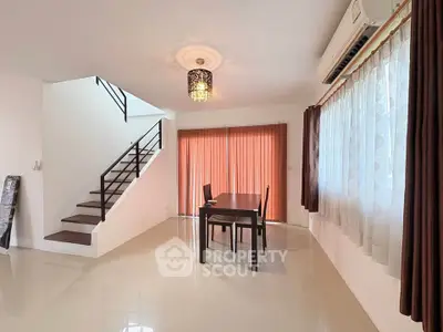 Spacious living room with modern staircase and elegant dining area in a bright, airy home.