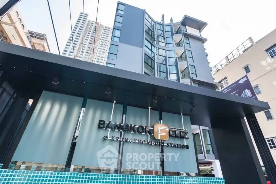 Modern condominium building with sleek design near public transit station.