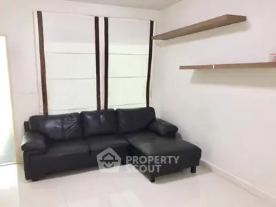 Modern living room with black leather sofa and minimalist shelves