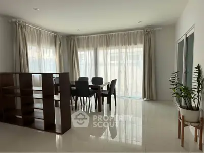 Spacious dining area with elegant curtains and modern furniture in a bright, airy room.