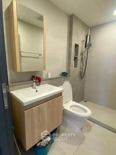 Modern bathroom with sleek fixtures and spacious shower area in contemporary apartment.