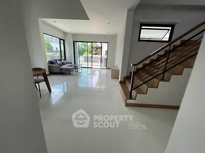 Spacious modern living room with large windows and elegant staircase