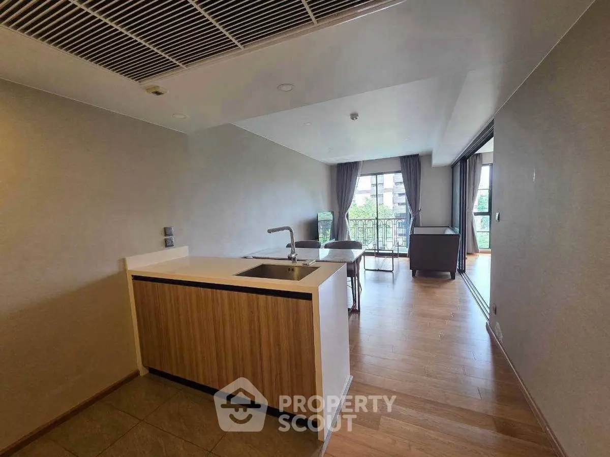 Modern open-layout kitchen with sleek design and spacious living area, featuring large windows and balcony view.