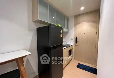 Modern compact kitchen with sleek black fridge and wooden cabinetry