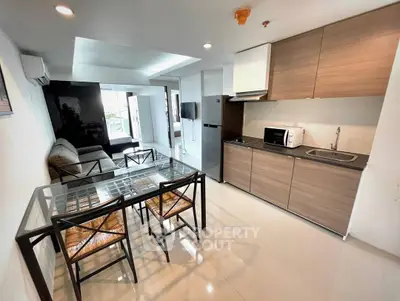 Modern open-plan living room with sleek kitchen and dining area, featuring contemporary furniture and appliances.