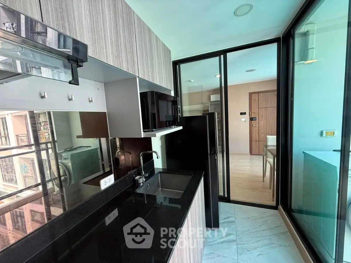Modern kitchen with sleek black countertops and glass partition in stylish apartment.