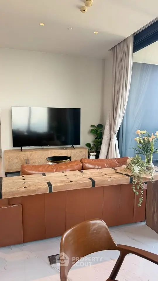 Luxurious living room with modern decor, large TV, and elegant leather sofa in a high-rise apartment.