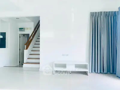 Bright minimalist living room with staircase and large window curtains.