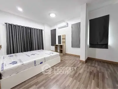 Spacious modern bedroom with sleek flooring and ample natural light.