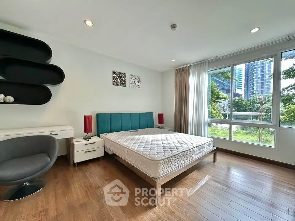 Spacious bedroom with modern decor and large window offering a scenic view.