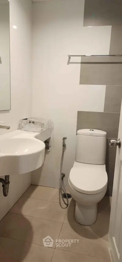 Modern bathroom with sleek fixtures and neutral tones, featuring a toilet and sink.