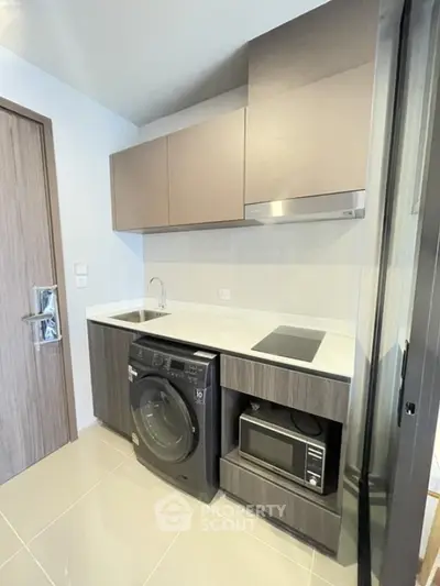 Modern compact kitchen with washing machine and microwave in sleek apartment