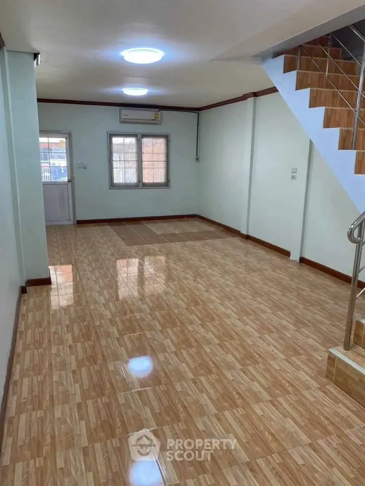 Spacious empty living room with tiled flooring and staircase, ideal for customization.
