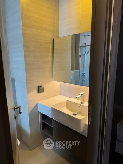 Modern bathroom with sleek sink and large mirror in stylish apartment.
