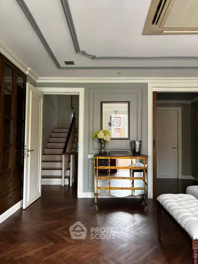 Elegant living room with wooden flooring and stylish decor, featuring a staircase and modern furnishings.