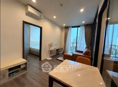 Modern living room with city view, featuring stylish furniture and large windows.