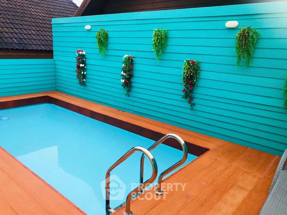 Charming rooftop pool with vibrant turquoise walls and decorative plants.