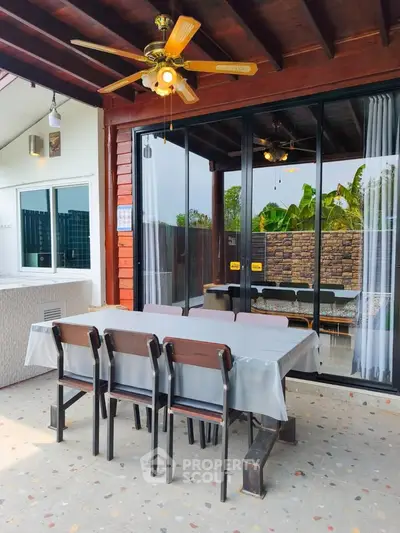 Charming outdoor dining area with ceiling fan and sliding glass doors leading to cozy interior.