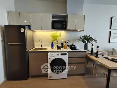 Modern kitchen with sleek cabinets, washing machine, and dining area in stylish apartment.