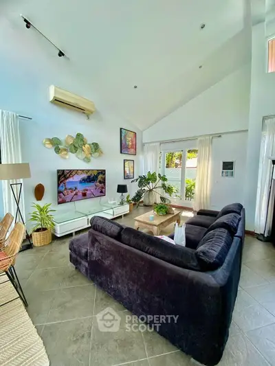 Spacious living room with high ceilings, modern decor, and large windows offering natural light.