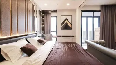 Luxurious bedroom with modern decor and balcony access in upscale apartment.