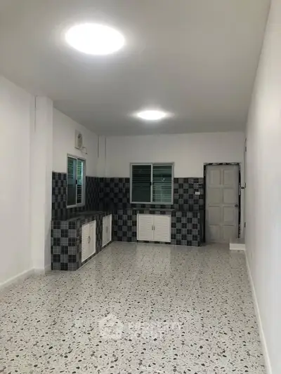 Spacious kitchen with terrazzo flooring and modern black-and-white tile accents.