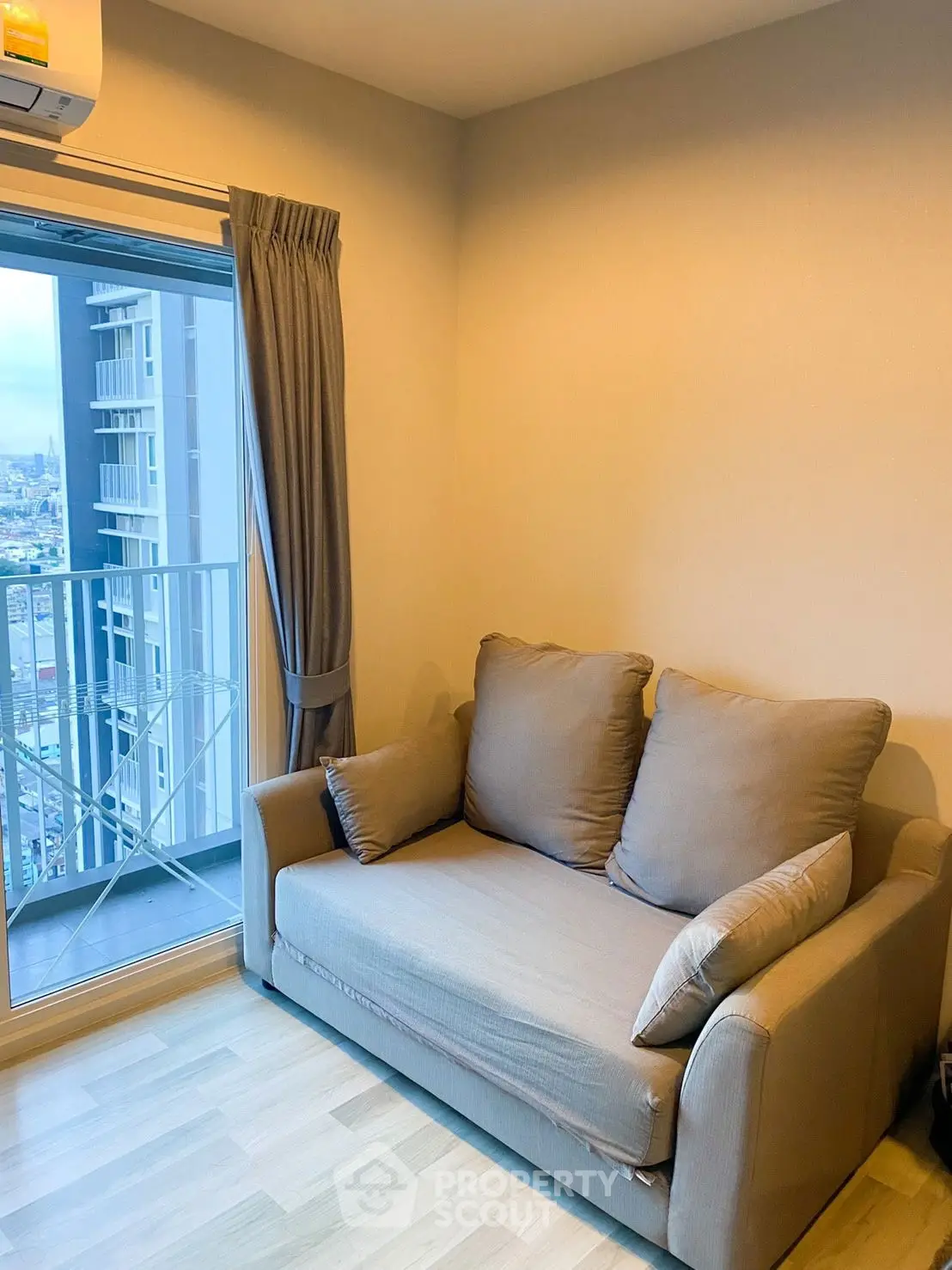 Cozy living room with a plush sofa and city view from the balcony, perfect for relaxation.