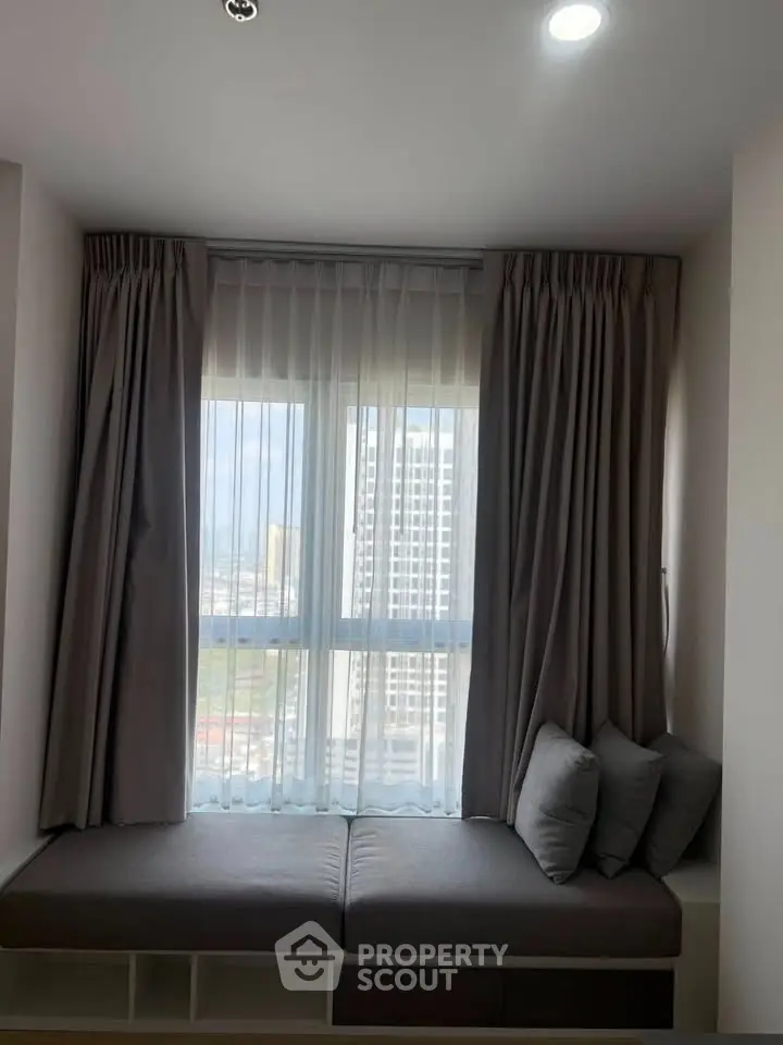 Cozy window nook with cushions and city view, perfect for relaxation in modern apartment.