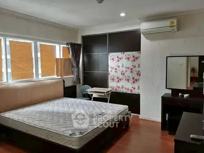 Spacious bedroom with large windows and modern furniture, perfect for comfortable living.