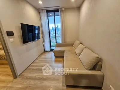 Modern living room with city view, featuring a sleek wall-mounted TV and cozy beige sofa.