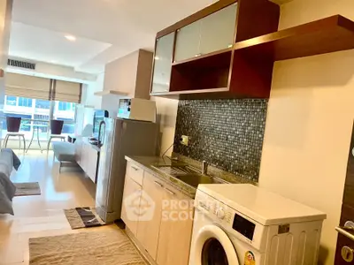 Modern open-layout kitchen with washing machine and dining area in a bright apartment.