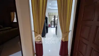 Elegant hallway with floor-to-ceiling curtains leading to a bright living area, showcasing modern interior design.