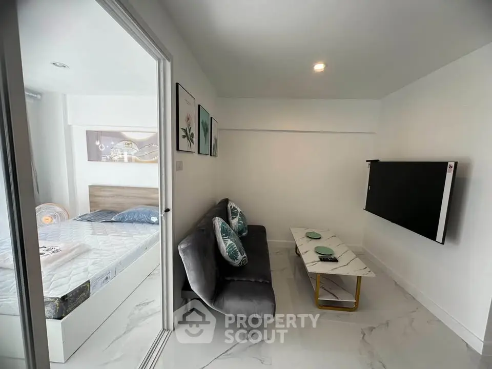 Modern studio apartment with sleek living area and cozy bedroom, featuring stylish decor and a wall-mounted TV.
