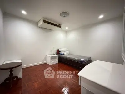 Minimalist bedroom with wooden flooring and single bed in a cozy apartment.