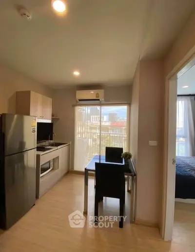 Modern apartment kitchen with dining area and view of bedroom, featuring sleek appliances and stylish decor.