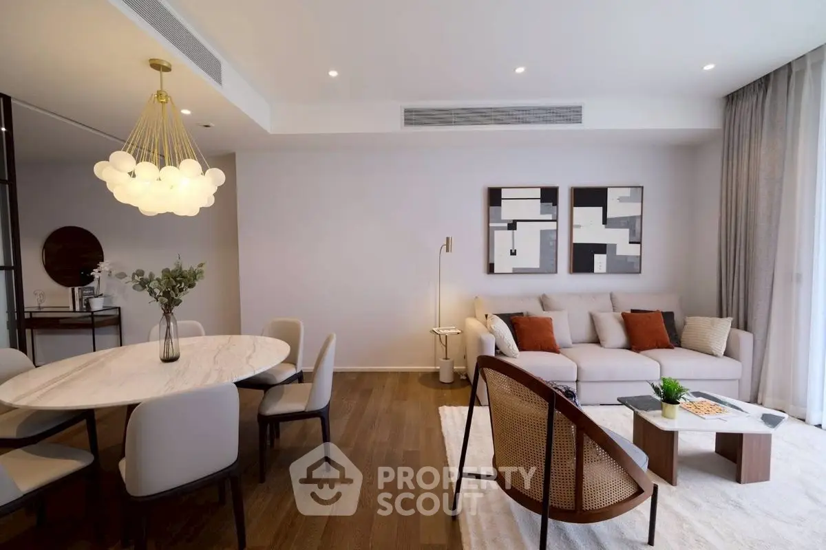 Elegant modern living room with stylish decor and open dining area, featuring contemporary furniture and warm lighting.