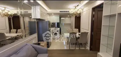 Luxurious open-plan living room and kitchen with elegant chandelier and modern appliances.