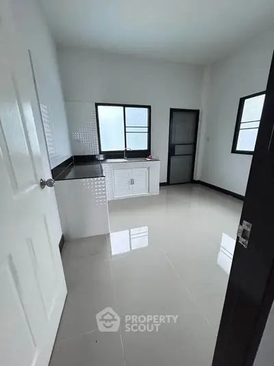 Spacious kitchen with sleek white cabinetry and large windows for natural light.