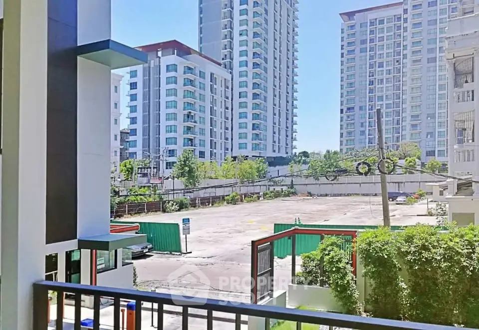 Modern urban apartment buildings with spacious parking area and lush greenery.