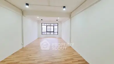 Spacious empty room with large windows and wooden flooring, perfect for customization.