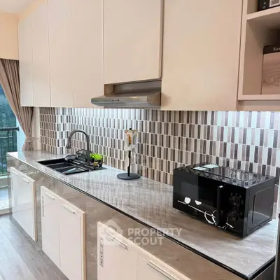 Modern kitchen with sleek cabinetry and stylish backsplash, featuring built-in appliances and ample counter space.