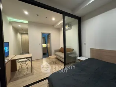 Modern studio apartment with glass partition, cozy living area, and sleek furnishings.