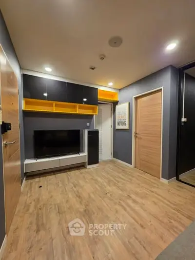Modern living room with sleek design and wooden flooring, featuring a TV unit and stylish storage solutions.