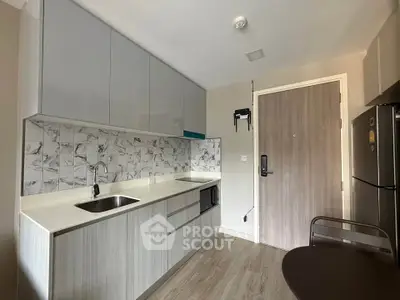 Modern kitchen with sleek cabinetry and marble backsplash in a compact apartment setting.